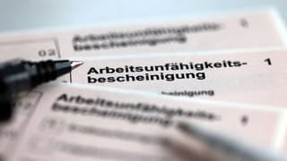 Stifte liegen auf Arbeitsunfähigkeitsbescheinigungen für Arbeitnehmer im Falle einer Krankschreibung durch den Arzt.