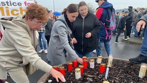 Angehörige und Freunde des Todesopfers stellen am Rande der Demo Kerzen auf.