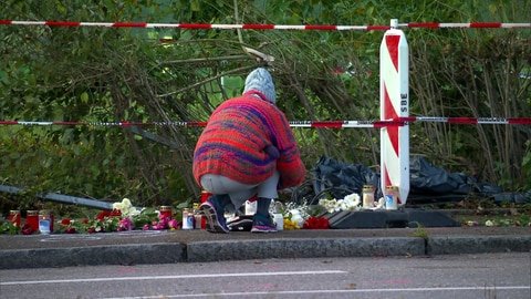 Eine Frau legt Blumen und Kerzen am Unfallort in Esslingen-Weil nieder. Eine Mutter und ihre drei und sechs Jahre alten Söhne sind am Dienstag von einem Auto erfasst worden, alle drei starben.