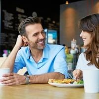 Ein Mann und eine Frau sitzen in einem Café beim Essen und schauen sich verliebt an.