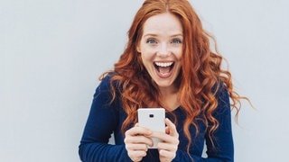 Junge Frau mit Smartphone in der Hand lacht über kuriose Redewendungen – wörtlich übersetzt von Deutsch auf Englisch, sehr schlecht – aber lustig.