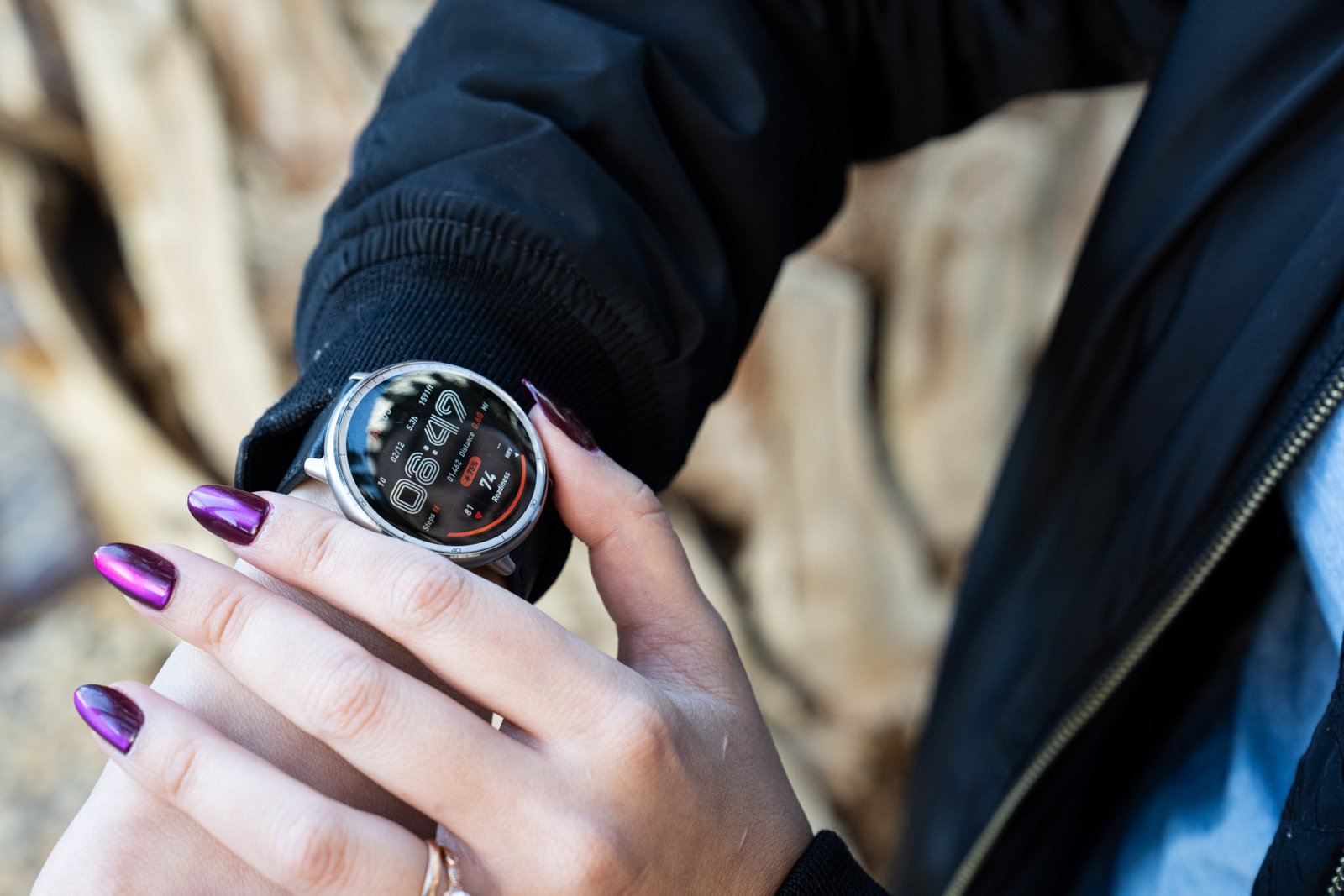 Nahaufnahme des Senior Rezensenten Victoria Song mit dem Amazfit Active 2, während er eine schwarze Jacke und lila Nägel trägt. Sie können einen verschwommenen Wüstenhintergrund sehen. 