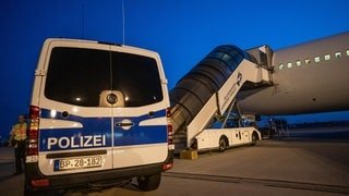 Ein Polizeiauto ist vor einer Abschiebung neben einer Fluggasttreppe zu sehen (Archivbild 2019).