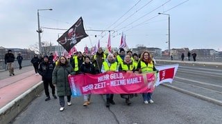 Streikende der Gewerkschaft ver.di halten gemeinsam ein Banner am Donnerstagmorgen in Mannheim.